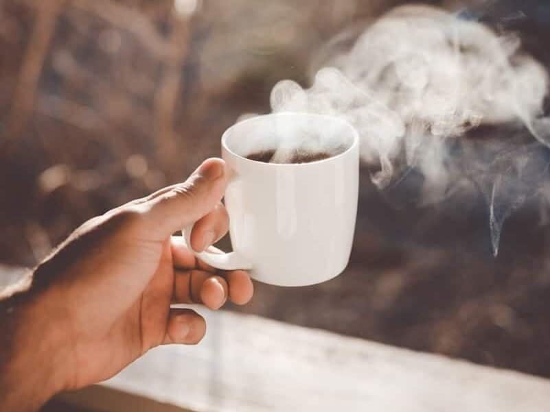 person holding white ceramic cup with hot coffee