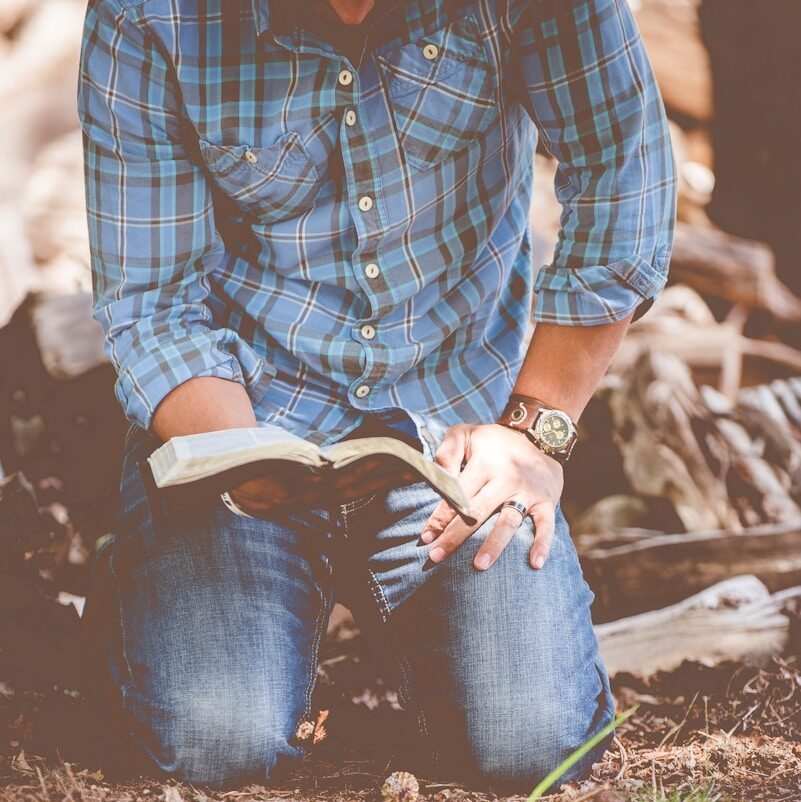 person reading book while kneeling