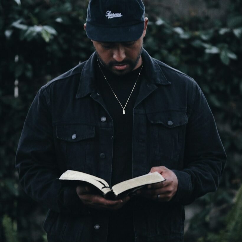 man in black jacket holding book